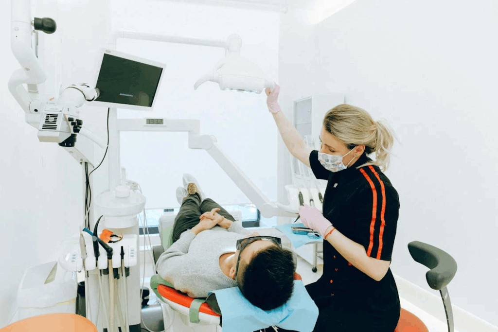 a dental professional adjusting the equipment as the patient lays on the dental chair